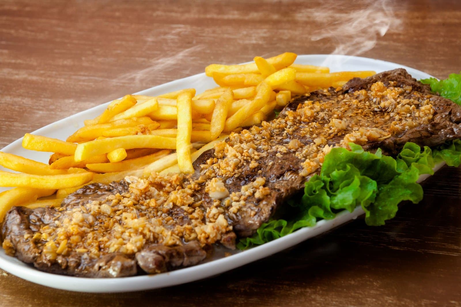 Picanha fatiada com farofa e batata frita, servida no Nikola's